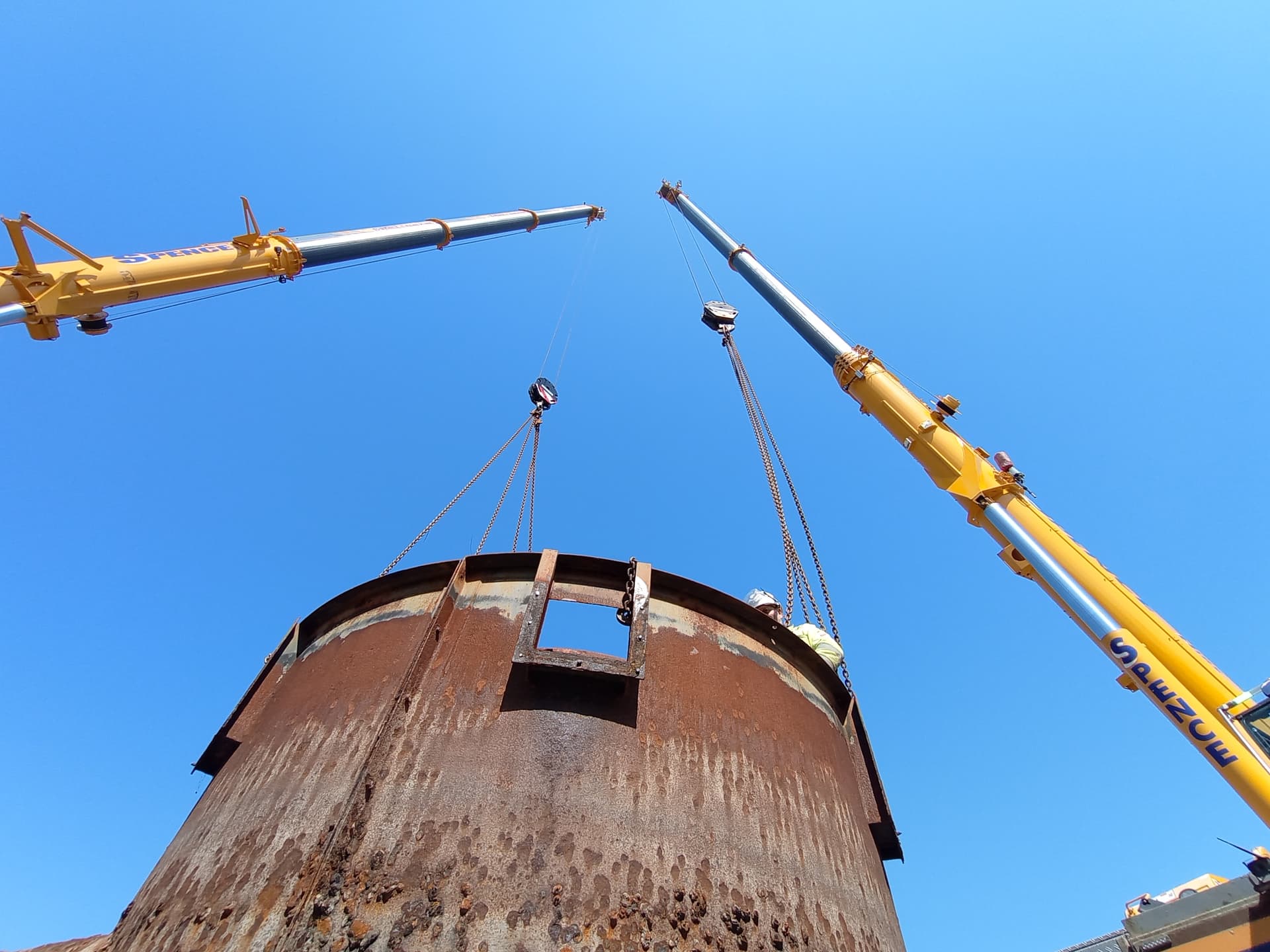 Twin cranes lifting a redundant tank clear of site