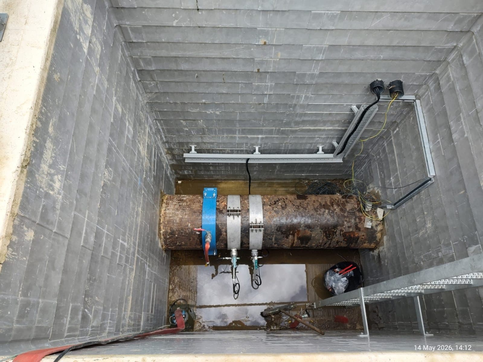 Tapping saddles fitted to a large diameter live water main in a chamber